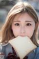 A girl in a school uniform eating a piece of bread.