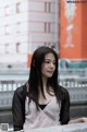 A woman with long black hair standing in front of a building.