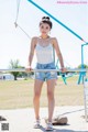 A woman in a white tank top and denim shorts posing for a picture.