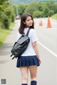 A woman in a school uniform is walking down the street.