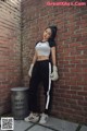 A woman leaning against a brick wall wearing boxing gloves.