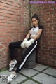 A woman sitting on top of a trash can wearing boxing gloves.