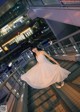 A woman in a white dress standing on a bridge.