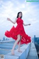 A woman in a red dress standing on a ledge.