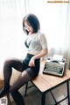 A woman sitting at a table with a typewriter.