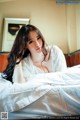 A woman laying on top of a bed in a white robe.