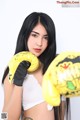 A woman in a white top and yellow boxing gloves.