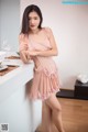 A woman in a pink dress standing next to a counter.