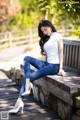 A woman sitting on a wooden bench in a park.