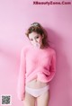 A woman in a pink sweater blowing a bubble gum.