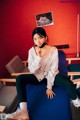 A woman sitting on a blue chair in a room.