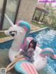 A woman sitting on an inflatable unicorn floating in a pool.