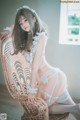 A woman sitting on a wicker chair wearing a white lingerie.