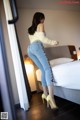 A woman in high heels standing in front of a bed.