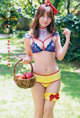 A woman in a bikini holding a basket of apples.