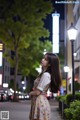 A woman standing in the middle of a city street at night.