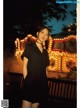 A woman in a black dress standing in front of a carousel.