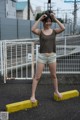 A woman standing on a yellow curb in front of a fence.